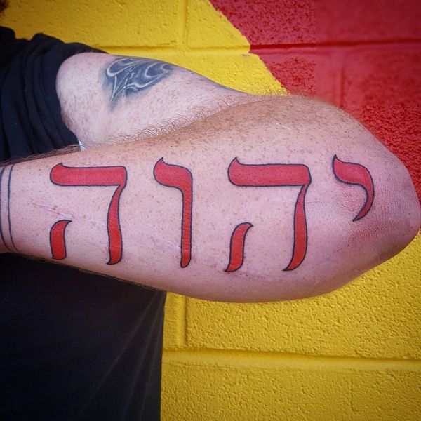 Насыщенный красным цветом тату на иврите на предплечье